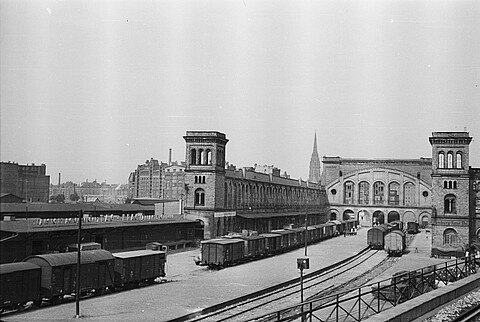 Schwarz-weiß Foto des Bahnhofsgebäudes, im Vordergrund Gleise.